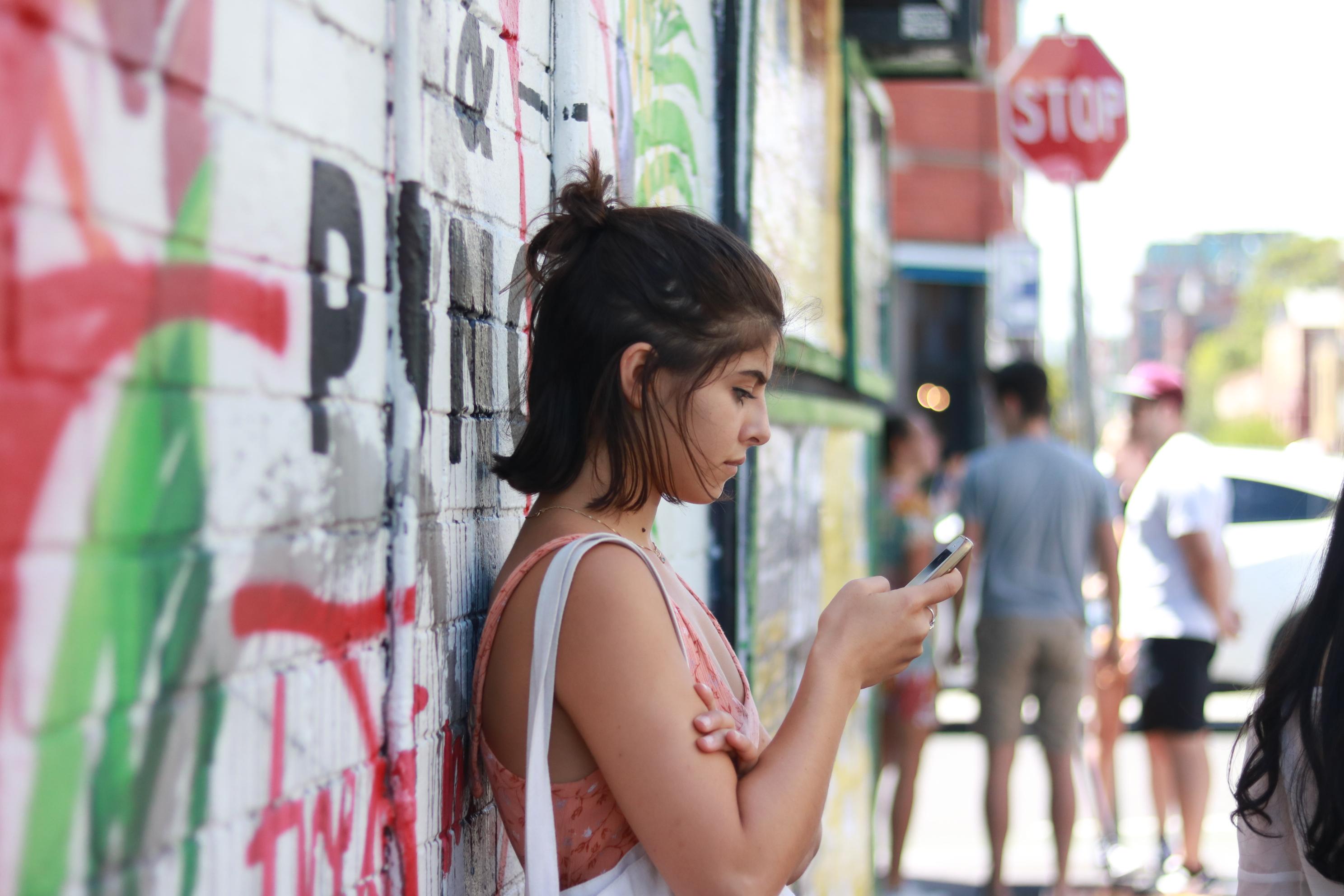 在附近的彩繪牆拍下的一個女孩滑手機等人的照片